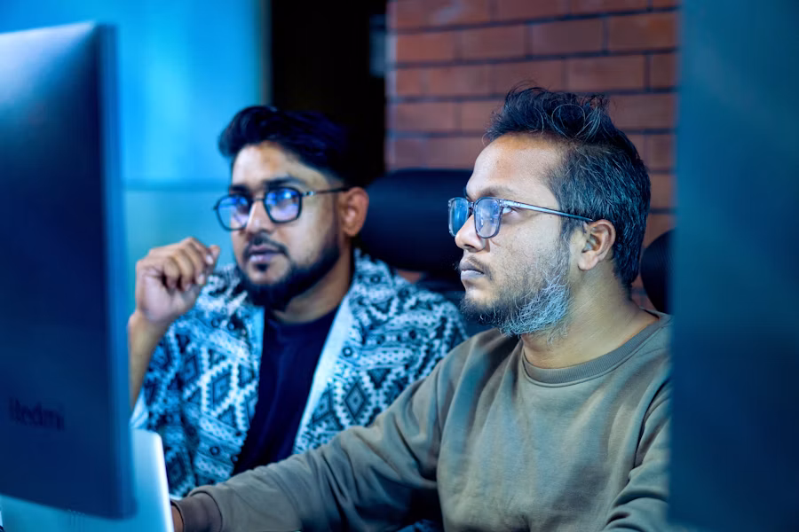 Two engineers reviewing a monitoring dashboard on a desktop screen